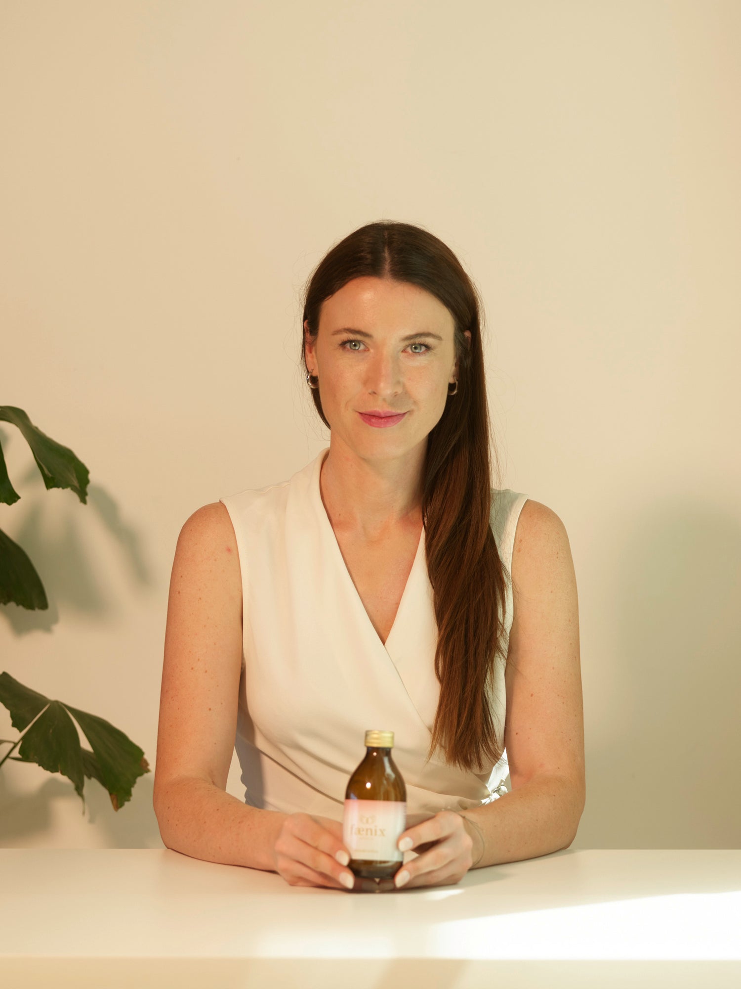 Woman holding a bottle against a plain background