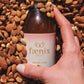 Hand holding a bottle labeled 'faenix elixir' surrounded by almonds